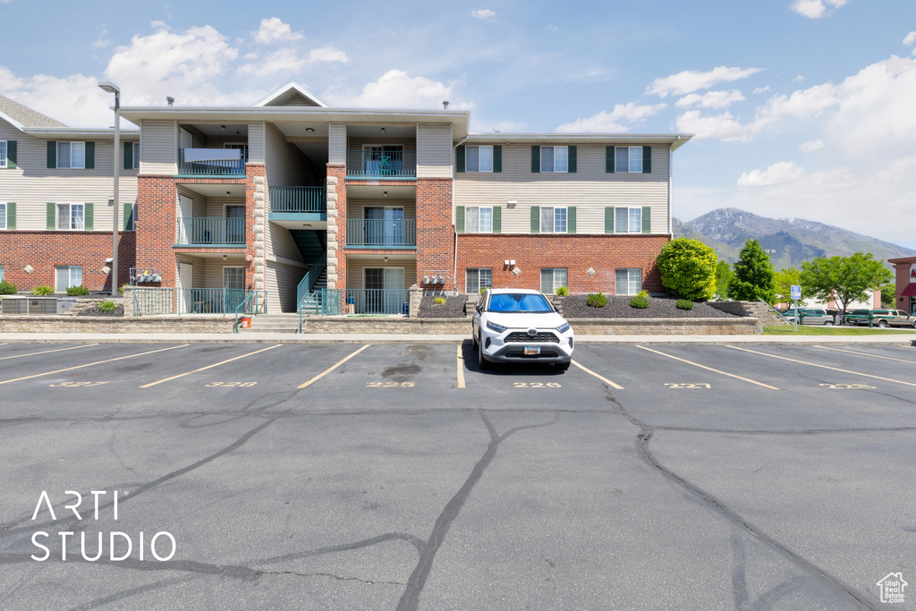 View of property with uncovered parking and a mountain view