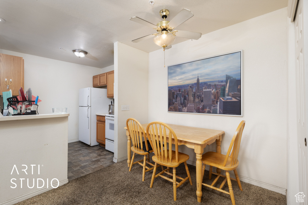 Dining space featuring a ceiling fan, baseboards, and dark carpet