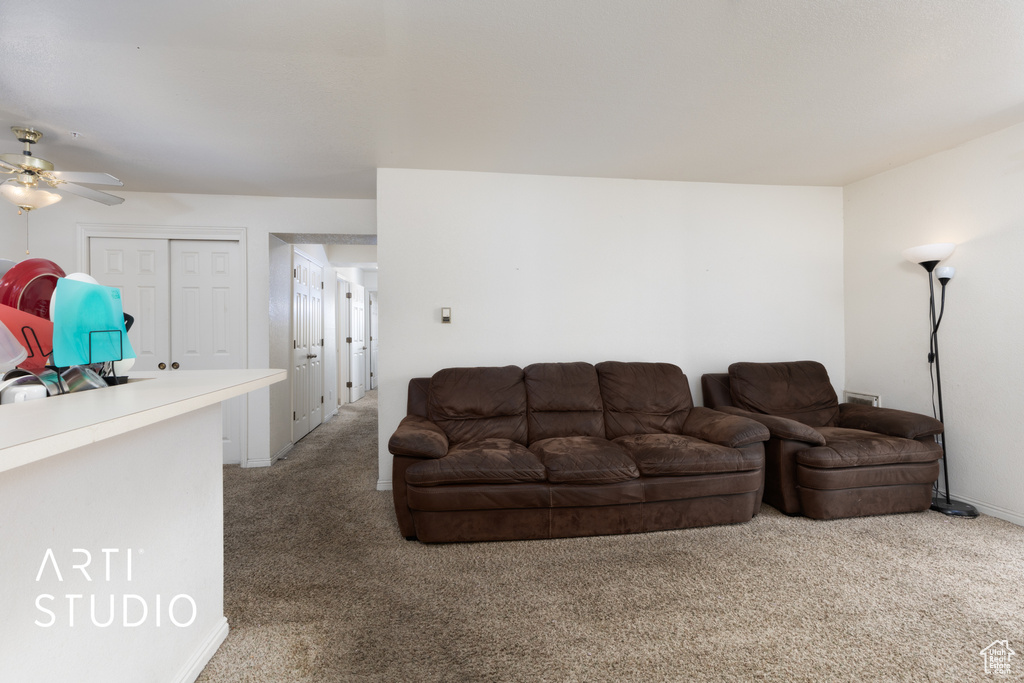 Living area with light colored carpet, ceiling fan, and baseboards