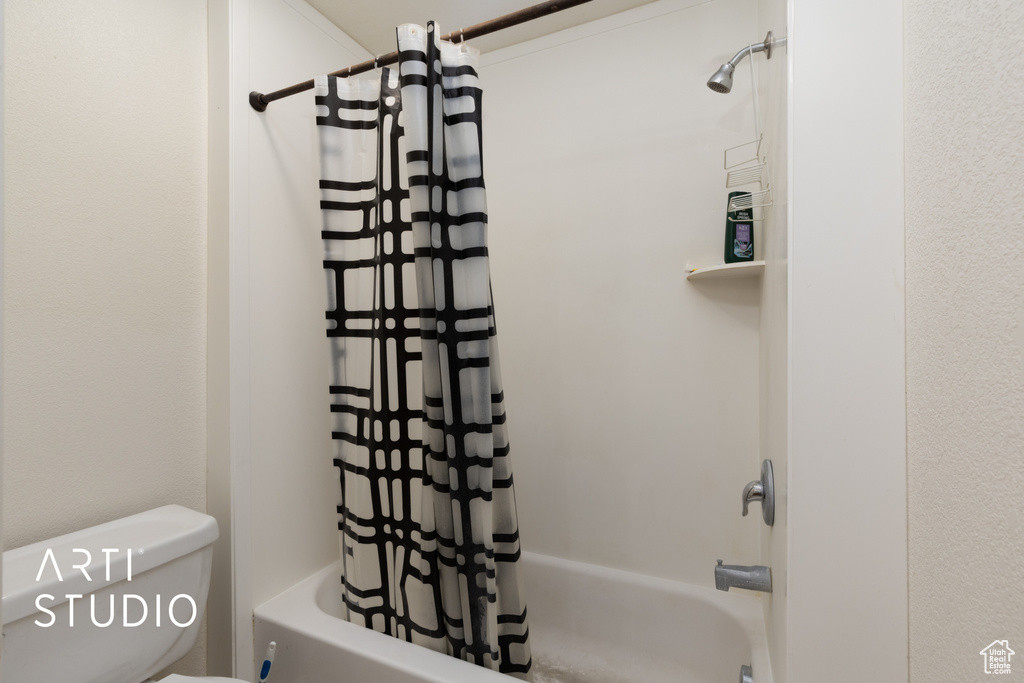 Full bathroom featuring shower / bathtub combination with curtain and toilet