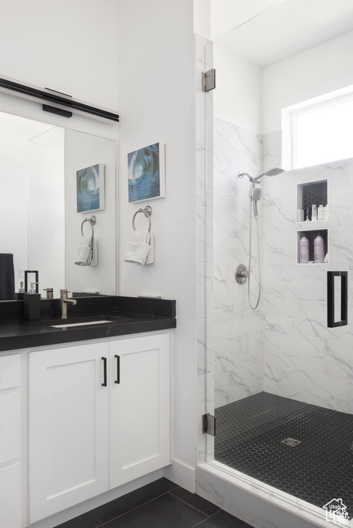 Full bath featuring a marble finish shower, vanity, and tile patterned flooring