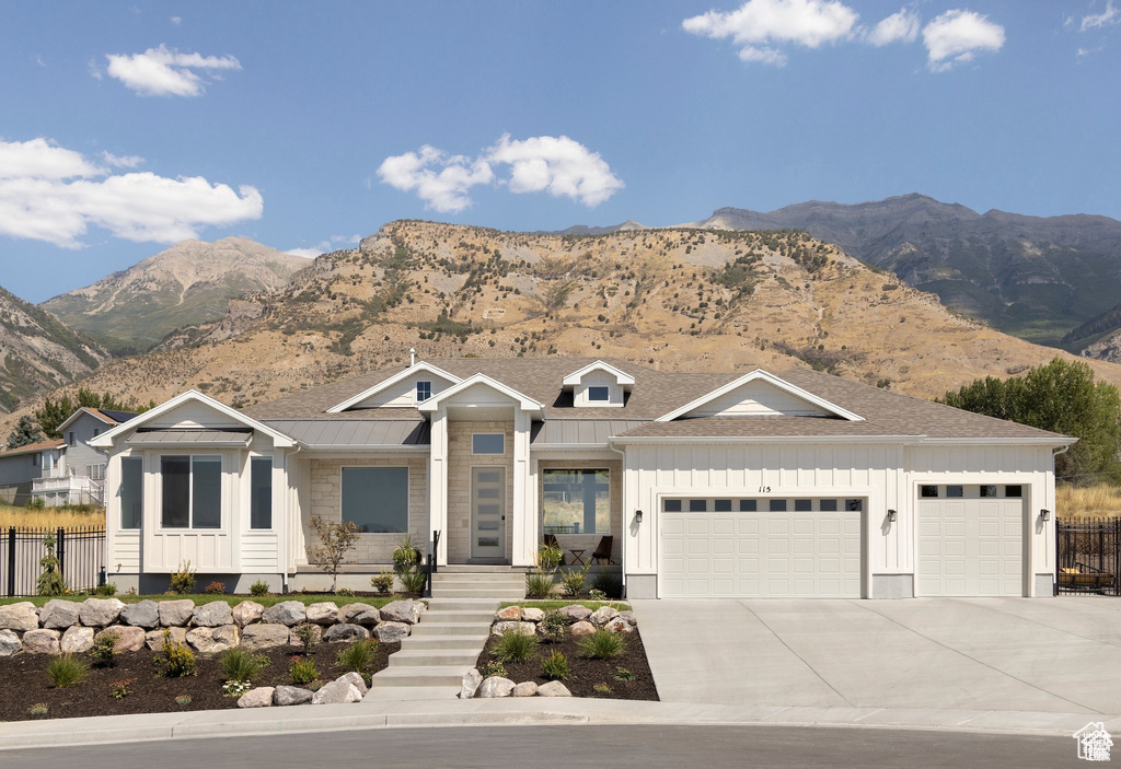 View of front of house featuring board and batten siding, a garage, a mountain view, driveway, and a standing seam roof