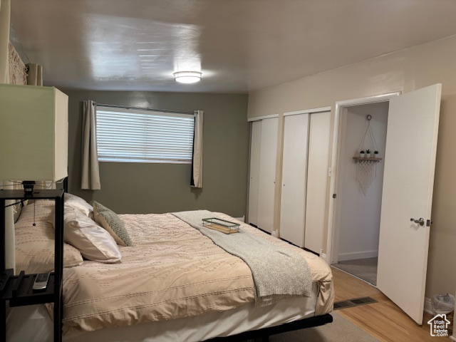 Bedroom with multiple closets and wood finished floors
