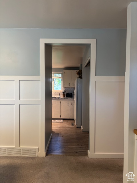 Hallway with carpet, wainscoting, and a decorative wall