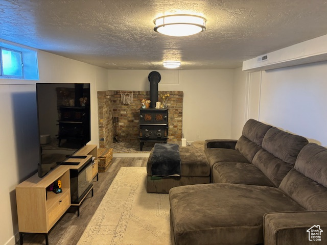 Living area featuring wood finished floors, a textured ceiling, and a wood stove