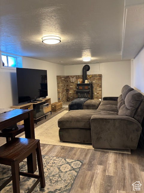 Living room with a wood stove, wood finished floors, and a textured ceiling