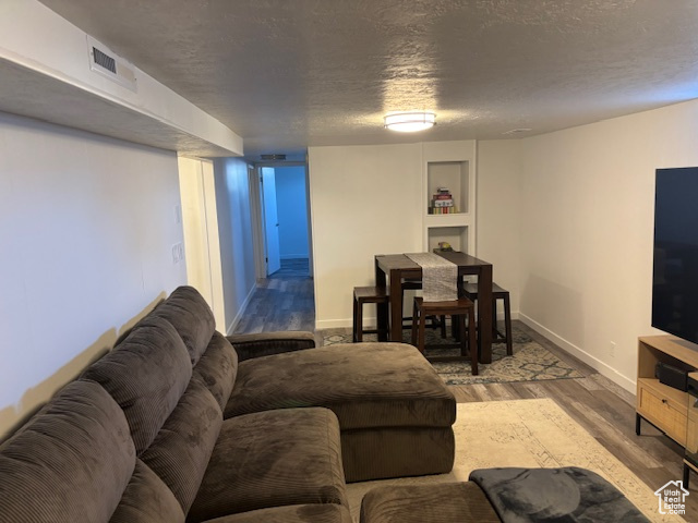 Living room featuring wood finished floors, a textured ceiling, and baseboards