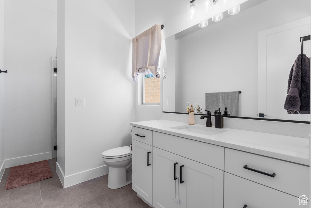 Bathroom with vanity, baseboards, toilet, and tile patterned floors