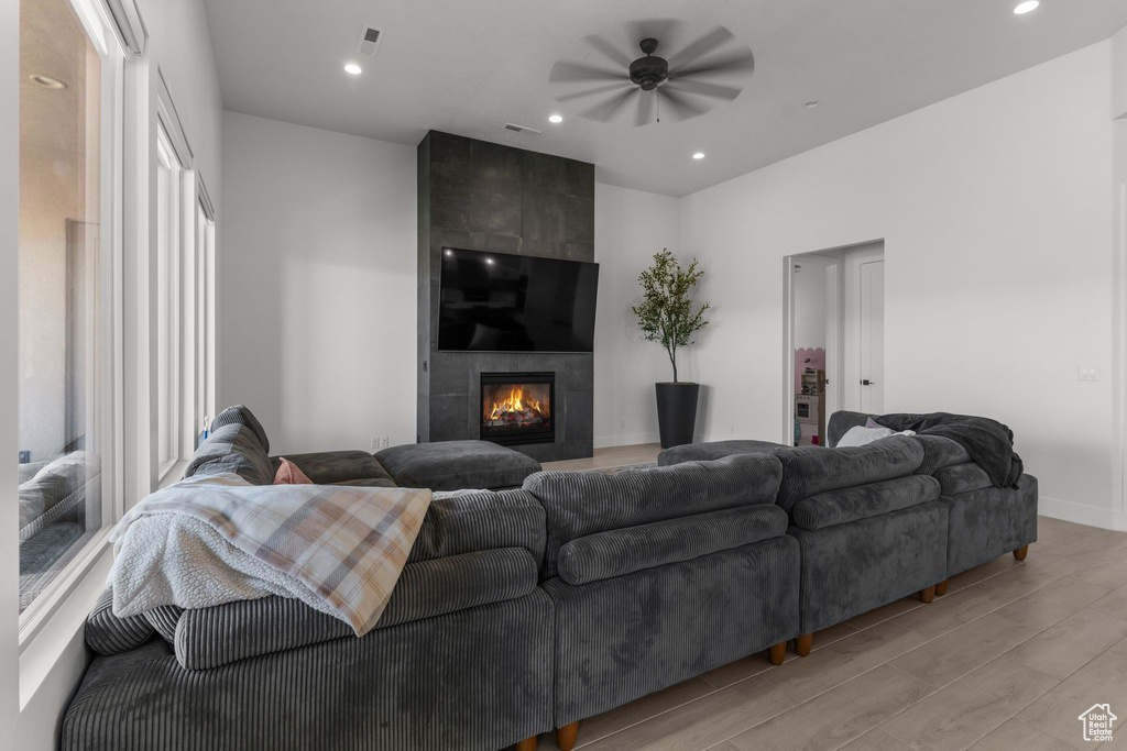 Living area with light wood-style flooring, a ceiling fan, a large fireplace, baseboards, and recessed lighting
