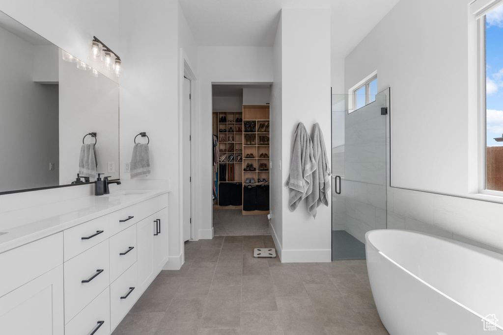 Bathroom featuring double vanity, a soaking tub, a stall shower, a spacious closet, and tile patterned floors