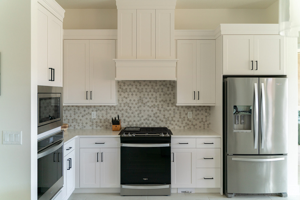 Kitchen with appliances with stainless steel finishes, light countertops, backsplash, and white cabinets
