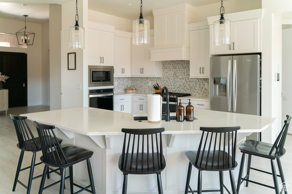Kitchen featuring appliances with stainless steel finishes, tasteful backsplash, and white cabinetry
