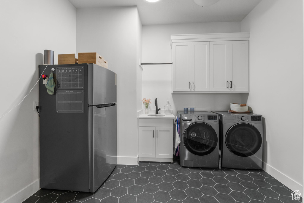 Laundry room with cabinet space, baseboards, independent washer and dryer, and dark tile patterned flooring