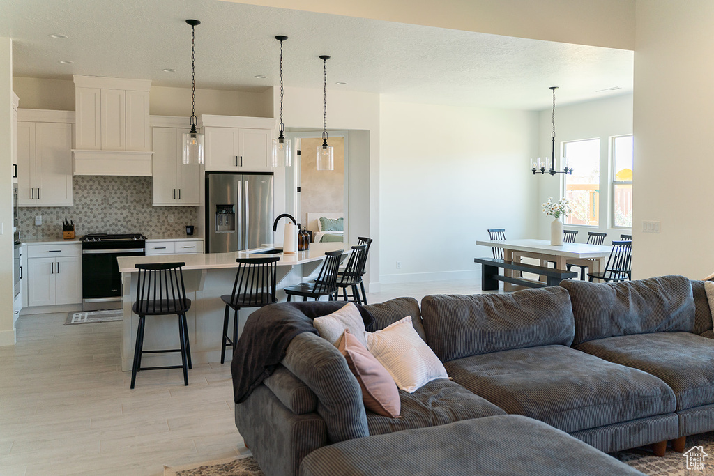 Living area featuring light wood-style floors, a chandelier, baseboards, and recessed lighting