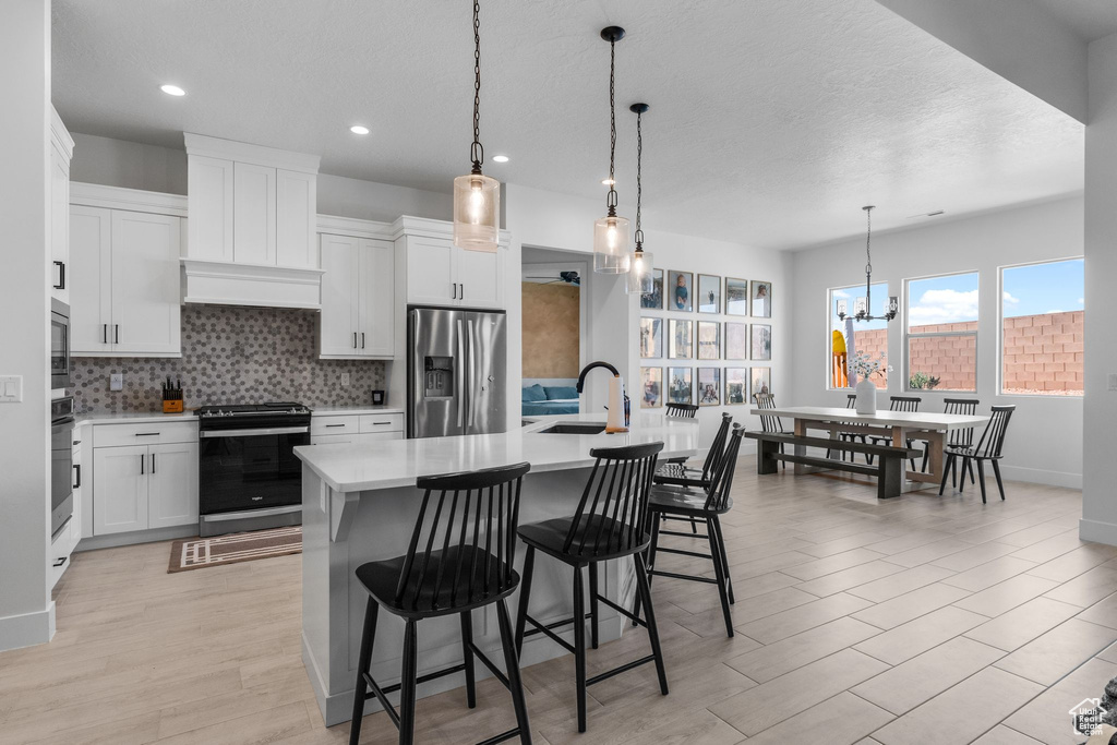 Kitchen with appliances with stainless steel finishes, light countertops, backsplash, a sink, and a chandelier