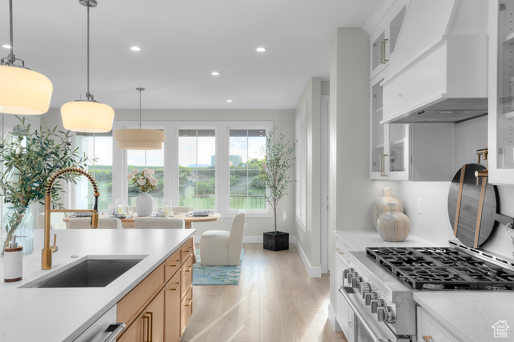 Kitchen with custom exhaust hood, a sink, light wood-style flooring, stainless steel stove, and recessed lighting