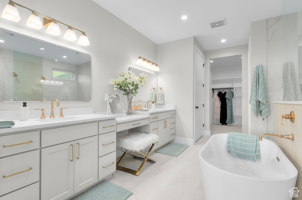 Full bath featuring marble finish floors, two vanities, a freestanding bath, recessed lighting, and a walk in shower