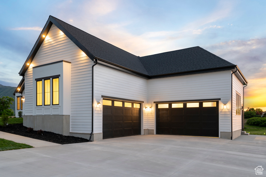 View of front of home featuring driveway, an attached garage, and a shingled roof