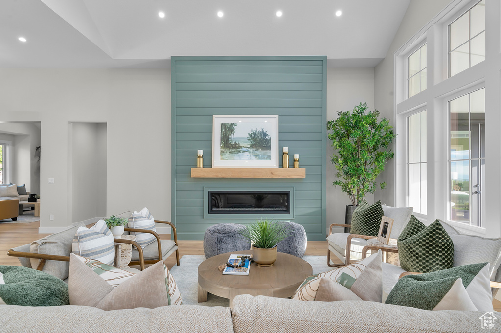 Living room featuring wood finished floors, recessed lighting, a large fireplace, vaulted ceiling, and baseboards