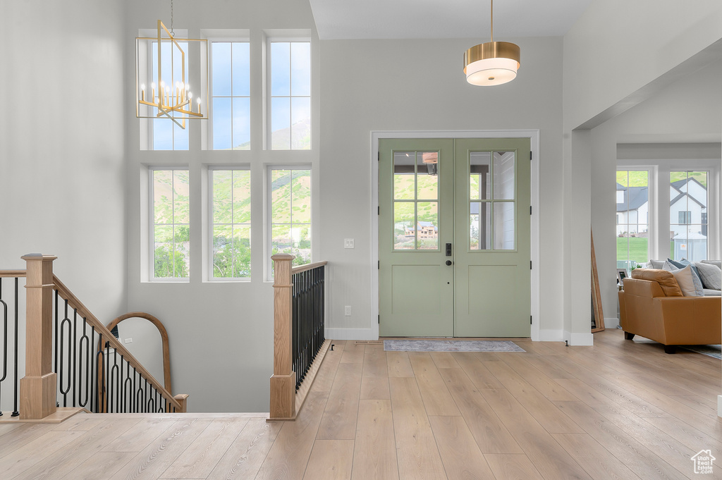 Foyer featuring a chandelier, a towering ceiling, baseboards, and hardwood / wood-style flooring