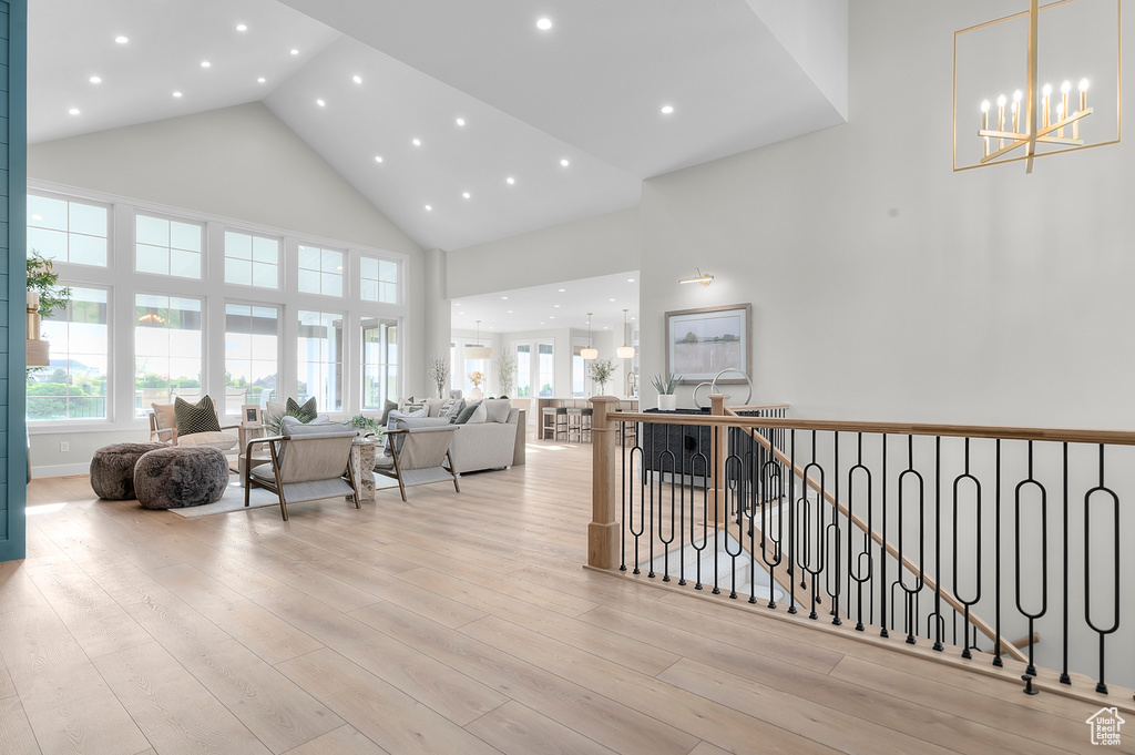 Hallway featuring high vaulted ceiling, an upstairs landing, wood finished floors, a chandelier, and recessed lighting