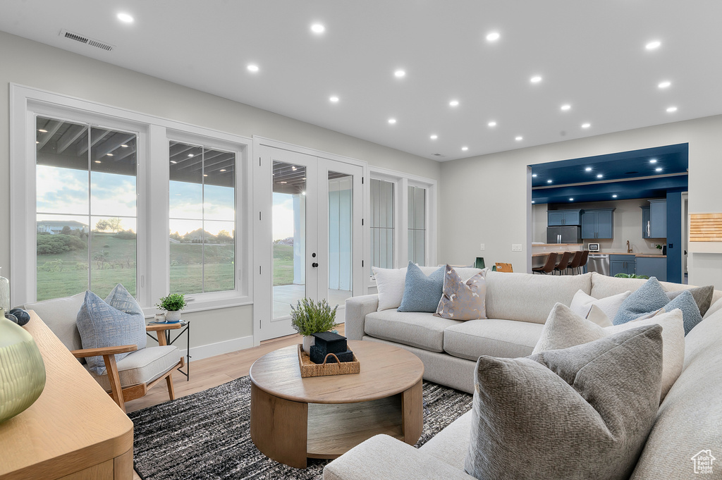 Living area with french doors, light wood-style flooring, and recessed lighting