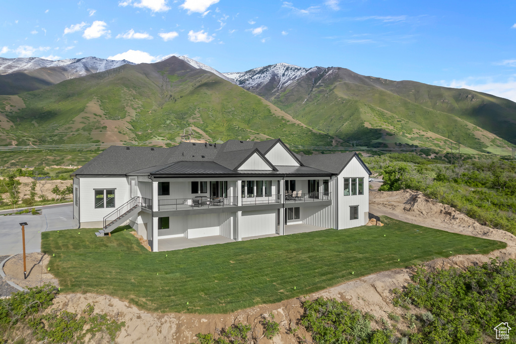 Back of house with stairway, a mountain view, a yard, and a balcony