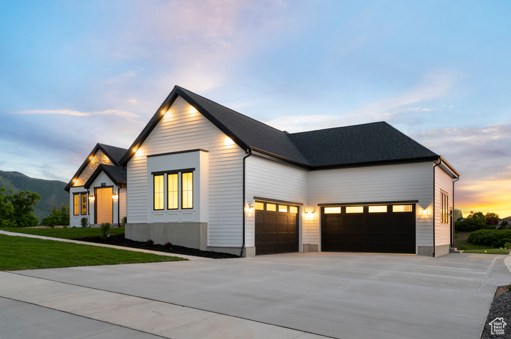 Modern farmhouse with driveway, an attached garage, a front yard, and a mountain view