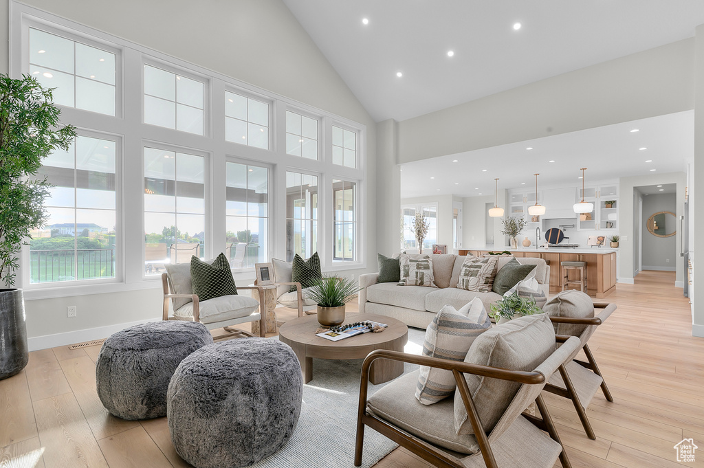 Living room featuring light wood finished floors, baseboards, high vaulted ceiling, and recessed lighting