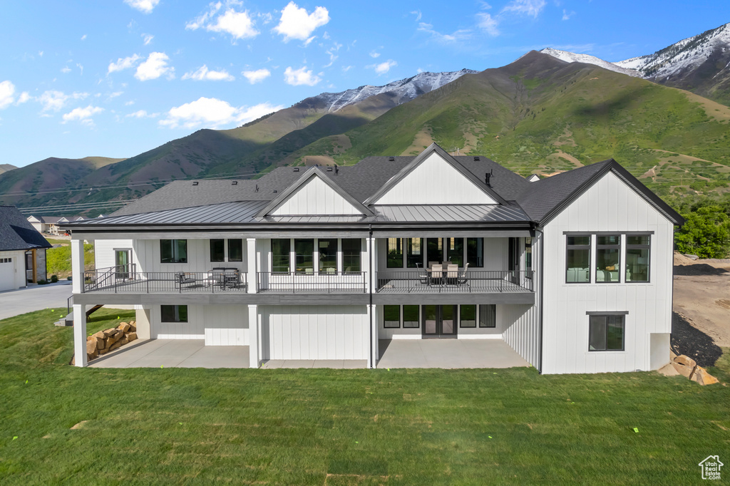 Back of property featuring a balcony, a patio, a standing seam roof, and a mountain view