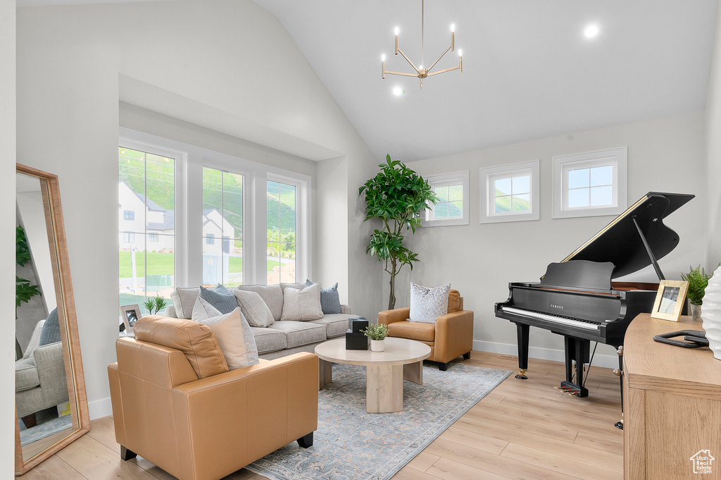 Living room with a chandelier, light wood finished floors, baseboards, recessed lighting, and high vaulted ceiling