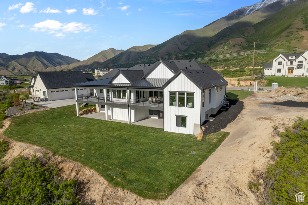 Back of property featuring a standing seam roof, driveway, a yard, and a mountain view