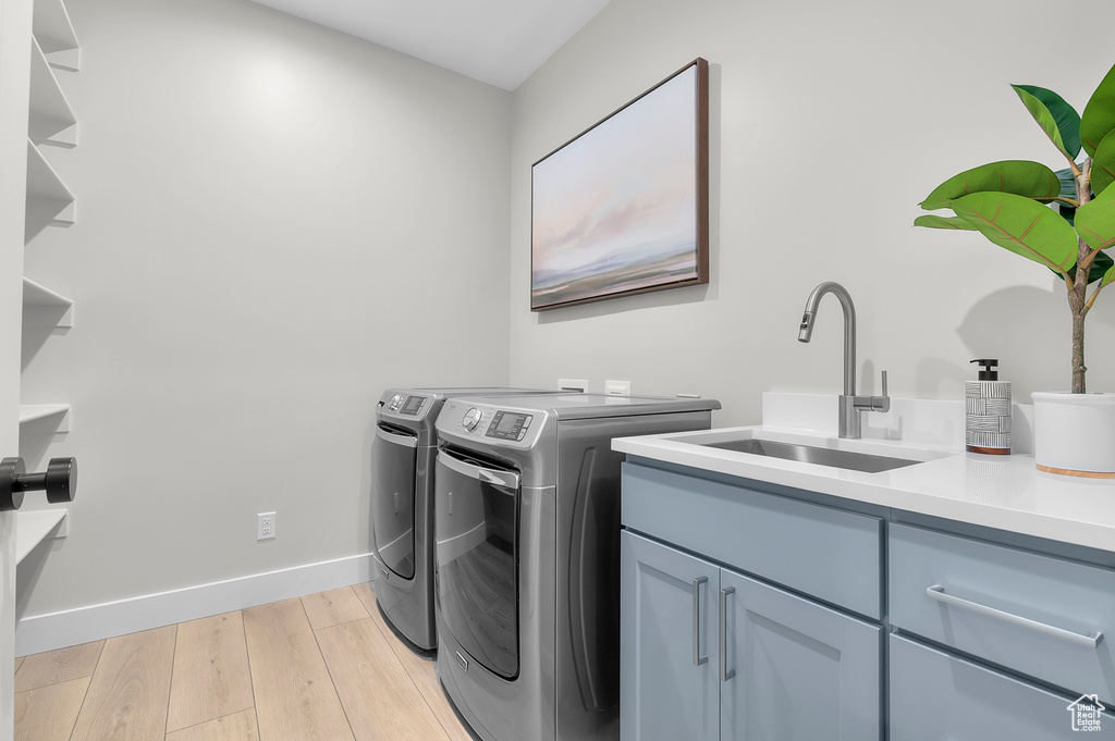 Laundry area with independent washer and dryer, cabinet space, light wood-type flooring, and baseboards