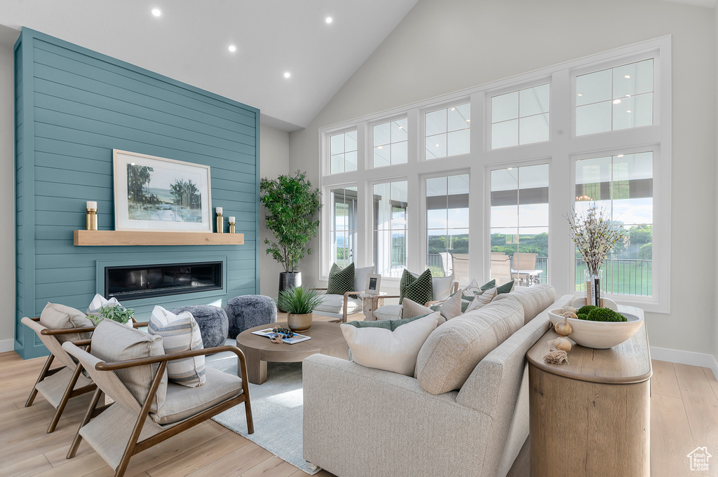 Living area featuring high vaulted ceiling, recessed lighting, light wood finished floors, a large fireplace, and baseboards