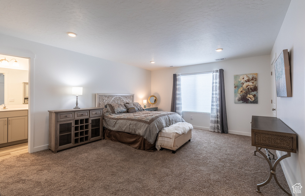 Bedroom featuring light colored carpet, ensuite bath, baseboards, and recessed lighting
