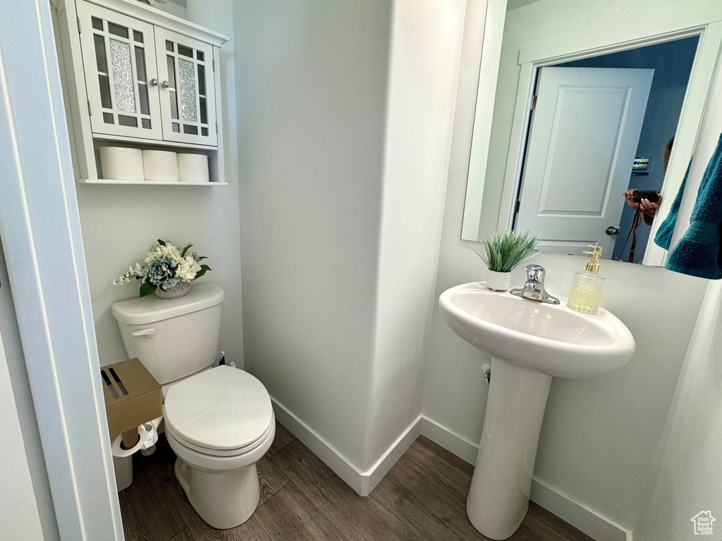 Bathroom featuring wood finished floors, toilet, and baseboards