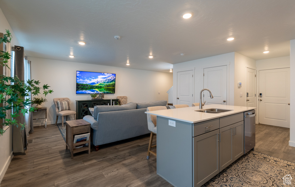 Kitchen with a sink, gray cabinetry, dishwasher, open floor plan, and dark wood-style floors