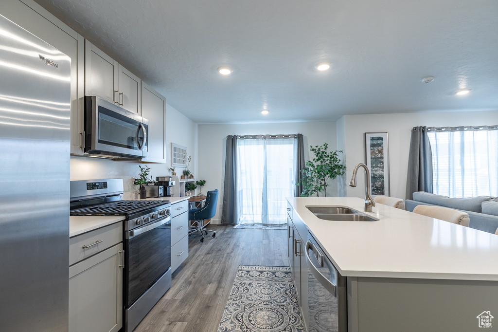 Kitchen with appliances with stainless steel finishes, a sink, gray cabinets, light countertops, and recessed lighting