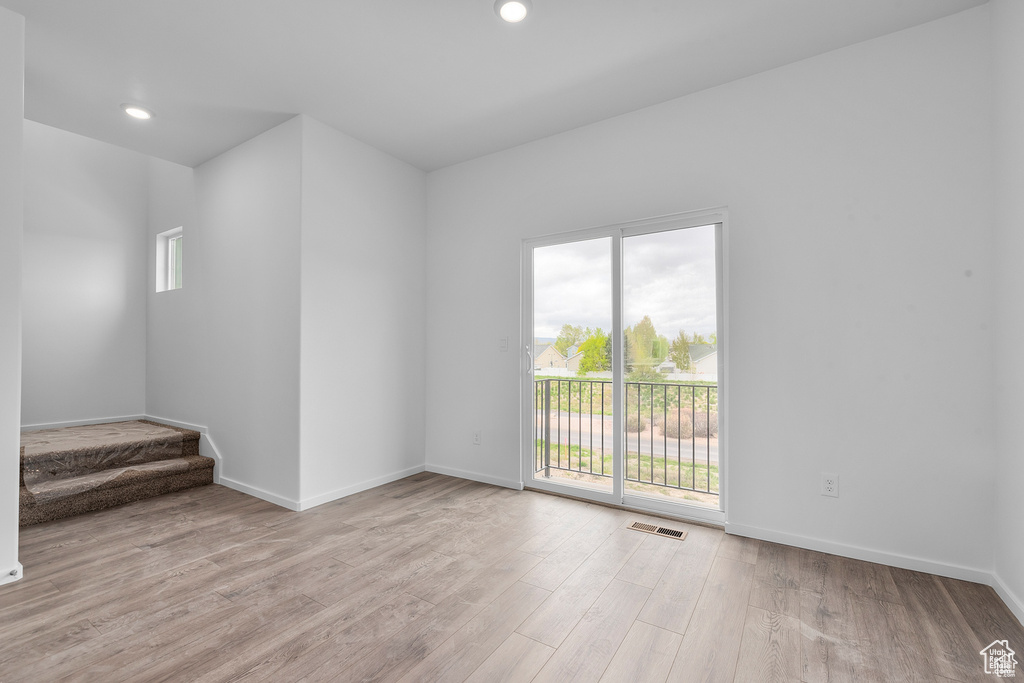Spare room with healthy amount of natural light, wood finished floors, baseboards, stairs, and recessed lighting
