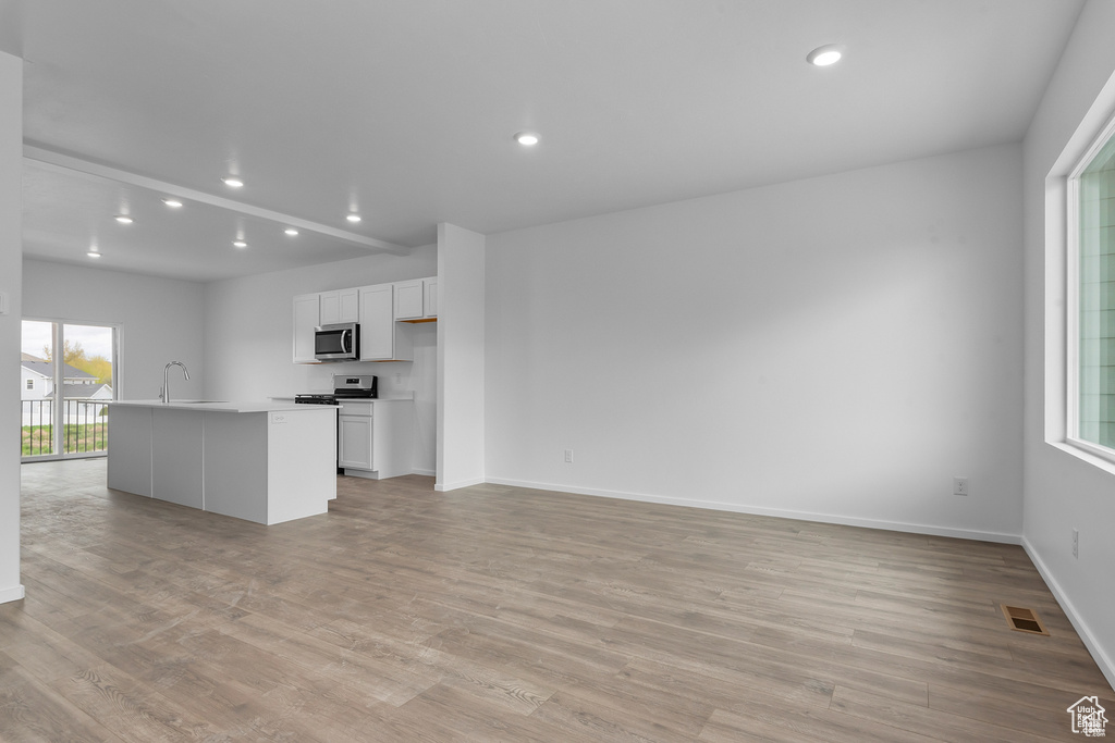 Kitchen featuring appliances with stainless steel finishes, light wood-style flooring, white cabinets, a sink, and recessed lighting