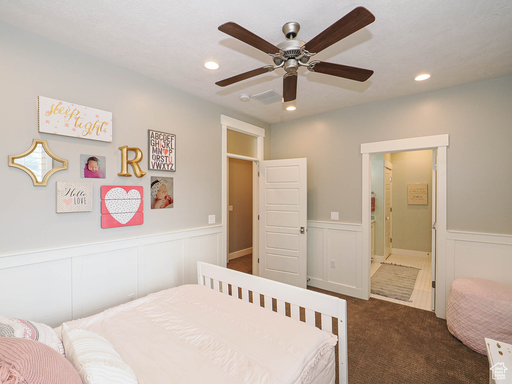 Bedroom featuring dark carpet, wainscoting, recessed lighting, a decorative wall, and ceiling fan