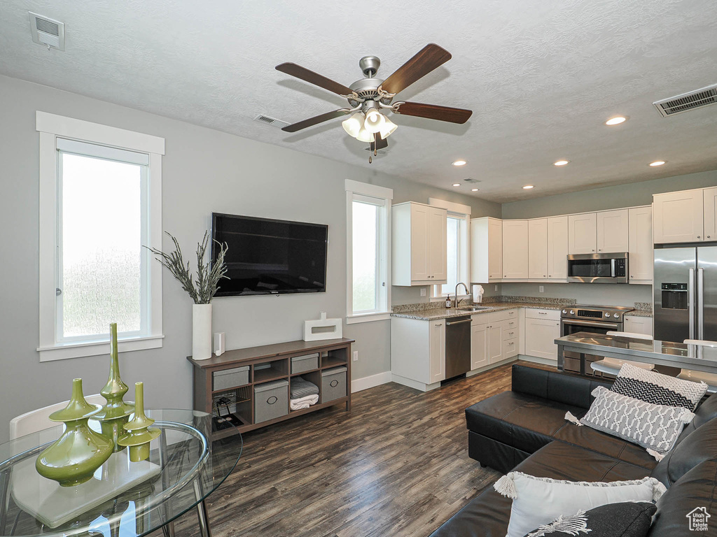 Living room featuring dark wood finished floors, ceiling fan, recessed lighting, baseboards, and a textured ceiling