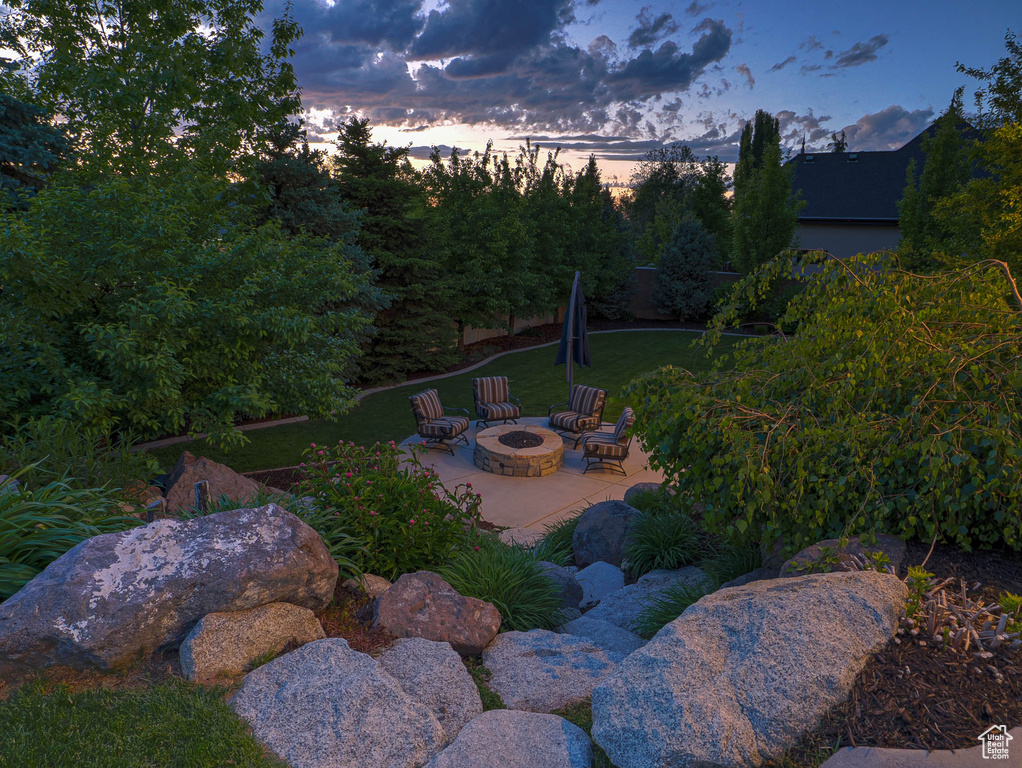 Yard at dusk featuring an outdoor fire pit and a patio