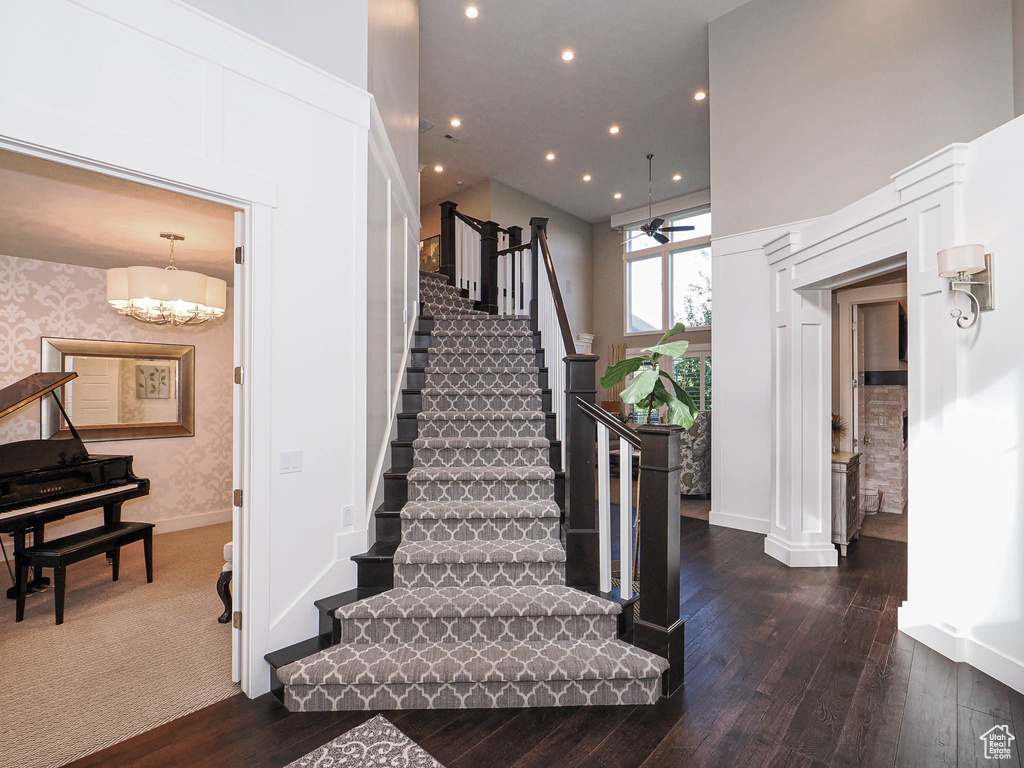 Stairs featuring a ceiling fan, hardwood / wood-style flooring, baseboards, recessed lighting, and a chandelier