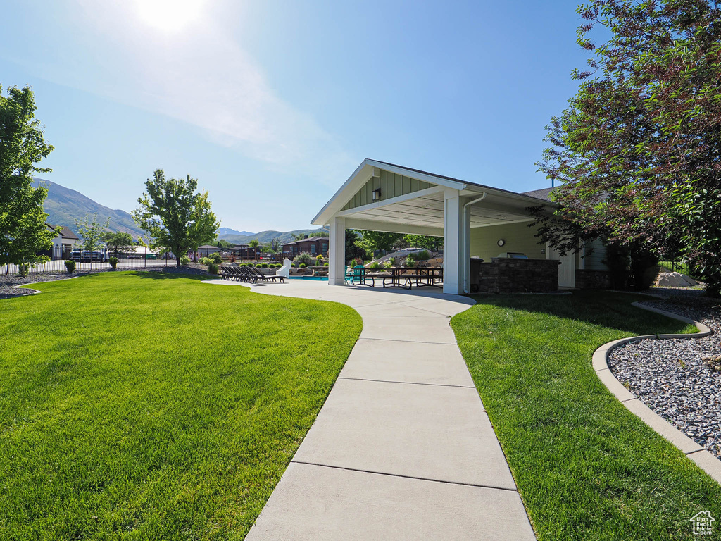 View of property's community with a lawn, a mountain view, a swimming pool, and a patio