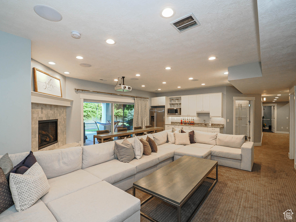 Carpeted living area featuring recessed lighting, a tile fireplace, and baseboards