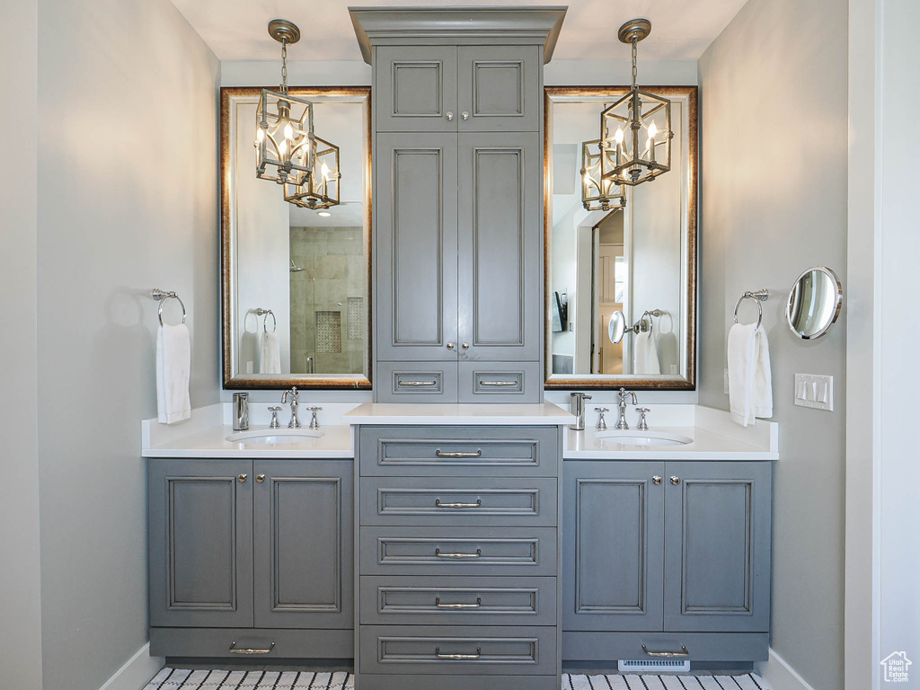 Bathroom with a chandelier, baseboards, and double vanity