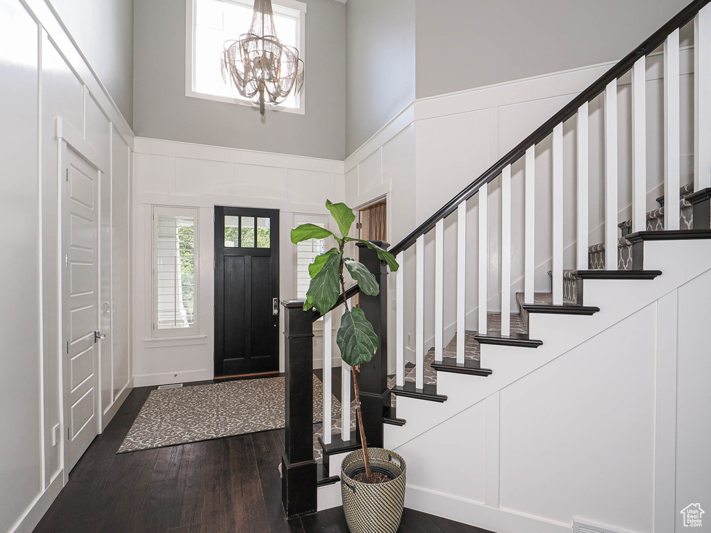 Entryway featuring dark wood-type flooring, stairway, a towering ceiling, and a chandelier