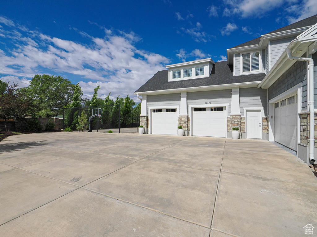 View of side of home featuring concrete driveway and stone siding