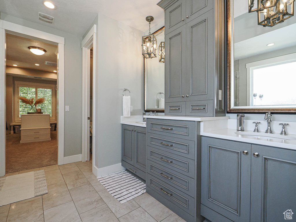 Full bath with a chandelier, vanity, and baseboards